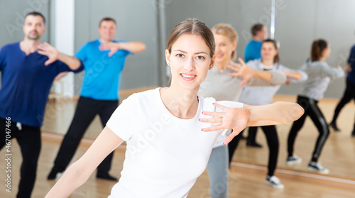 Portrait of young emotional woman doing exercises during group class in dance center