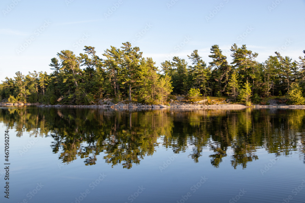 Pinetree reflecting in the water along the rocky shore of Franklin Island on Georgian Bay on a calm summer day Pinetree reflecting in the water along the rocky shore of Franklin Island on Georgian Bay on a calm summer day