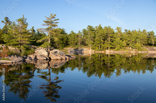 Fototapeta Naklejka Na Ścianę i Meble -  Pinetree reflecting in the water along the rocky shore of Franklin Island on Georgian Bay on a calm summer day