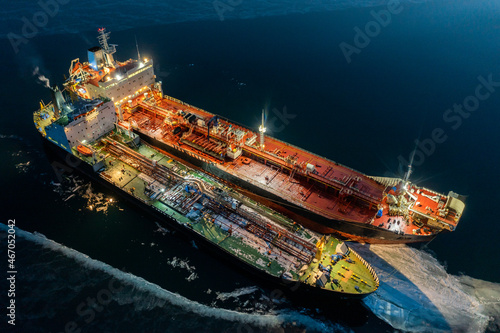 Two tankers at night, stand nearby in young ice. Shooting from air.