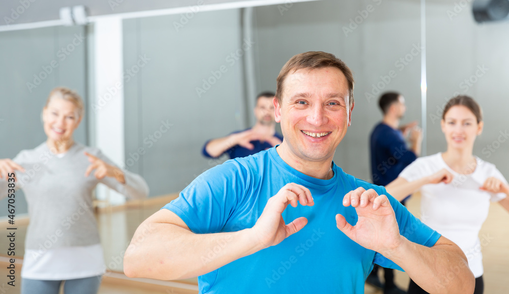 Fototapeta premium Portrait of cheerful adult man enjoying vigorous dances in modern dance studio
