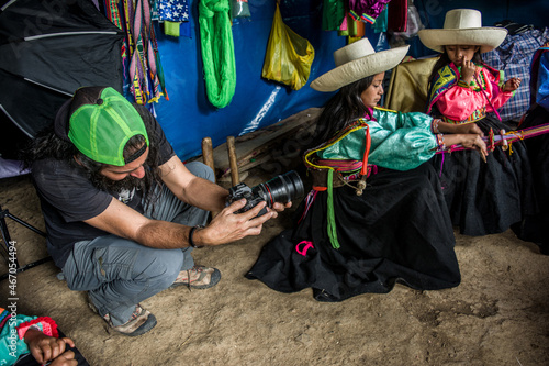 Fotógrafo  realiza fotografías a dos niñas latinoamericanas andinas que tejen con el telar de cintura photo