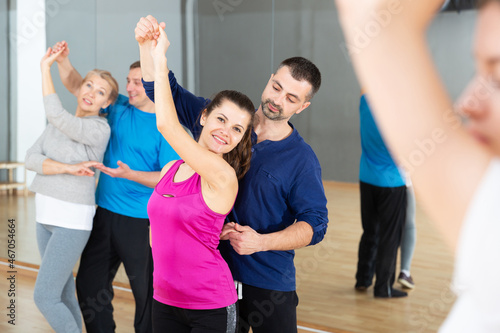 Group of happy adult people dancing modern social dances in pair at .dance school