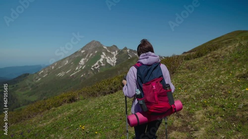 Girl backpacker climbing mountains with trekking poles