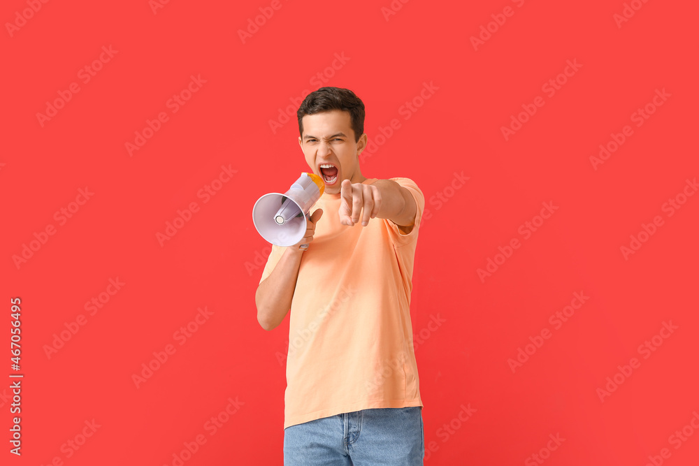 Protesting young man with megaphone on color background Protesting young man with megaphone on color background