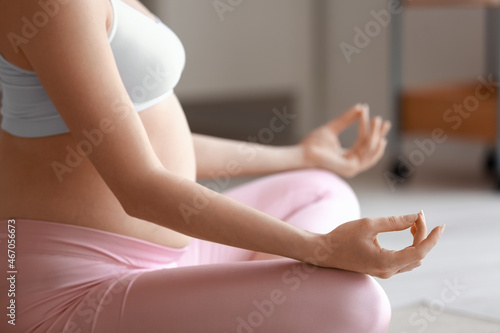 Young pregnant woman meditating at home in morning