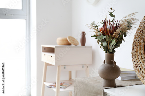 Vase with beautiful bouquet of dried flowers on chest of drawers in light room © Pixel-Shot
