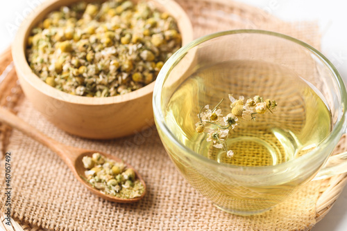 Chamomile tea in a cup glass with dried chamomile flowers in a bowl and spoon, Healthy herbal tea