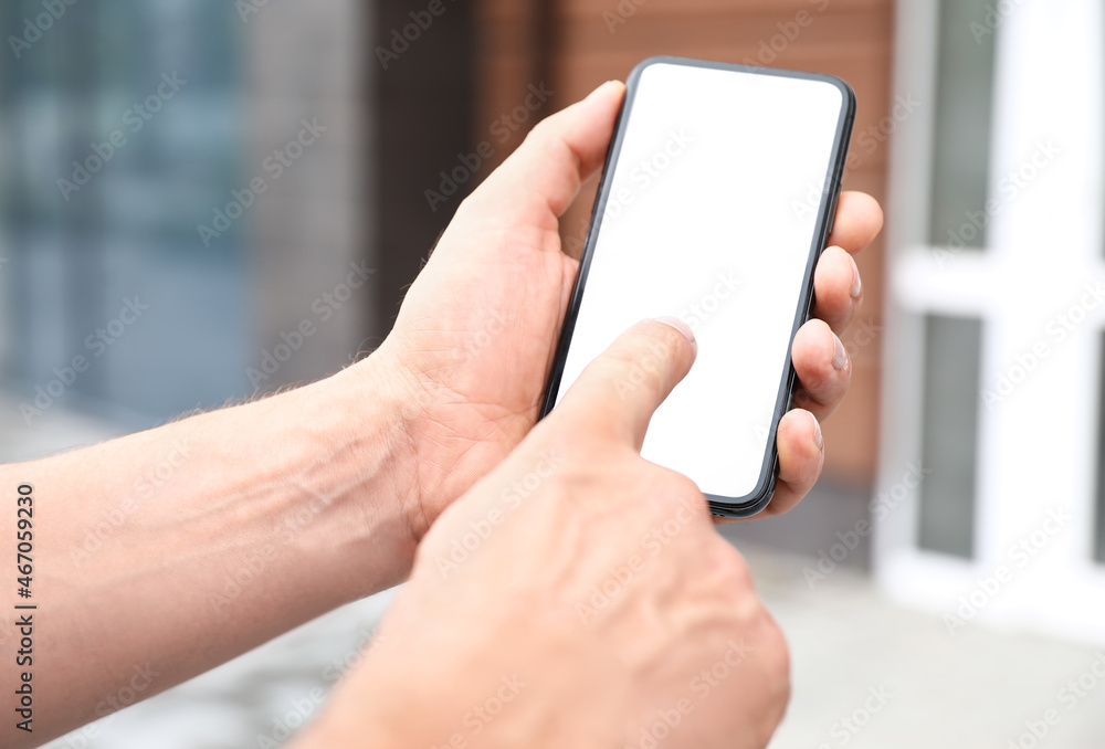 Man using mobile phone with blank screen outdoors, closeup
