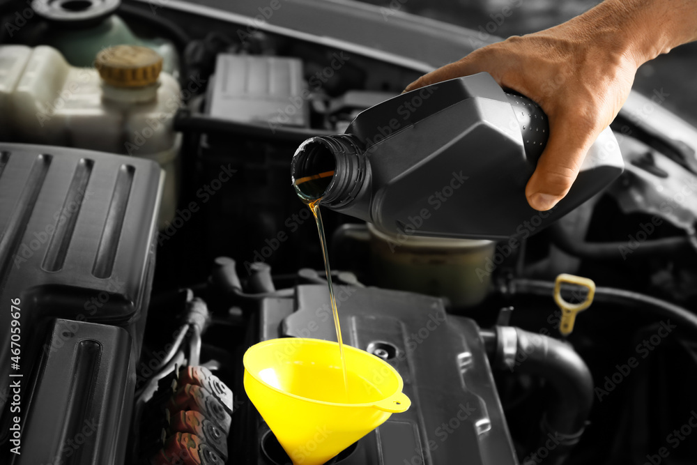 Male mechanic pouring motor oil from canister into car engine Male mechanic pouring motor oil from canister into car engine