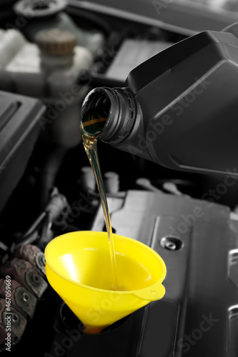 Pouring motor oil from canister into car engine