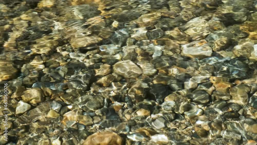 The stream of water through which the stony bottom of the river is visible. The stream of water through which the stony bottom of the river is visible.