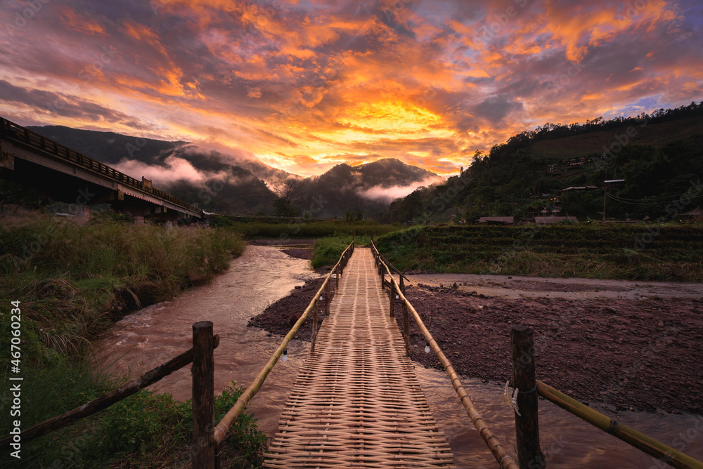 Beautiful landscape scenic of the wooden bamboo bridge with the fog and dramatic sky background in sunset time at Sapun in Nan province, Northern of Thailand.