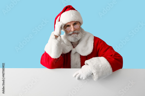 Santa Claus with blank poster on color background