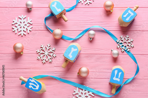 Dreidels and Christmas decor on color wooden background