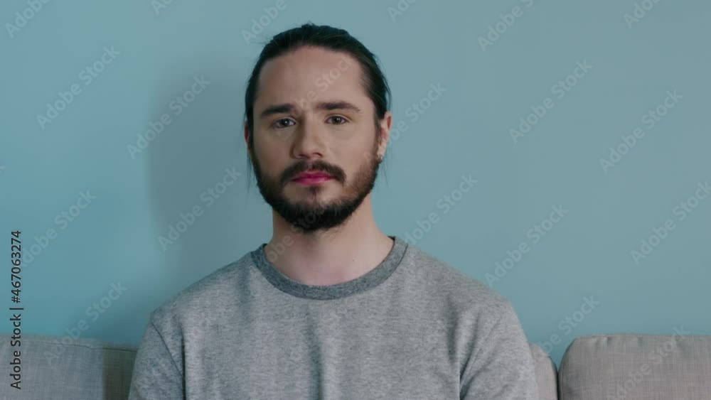 Portrait of young man sitting on sofa at home, tired and under stress, losing hope on the future of his dream, Caucasian white, slow motion. Portrait of young man sitting on sofa at home, tired and under stress, losing hope on the future of his dream, Caucasian white, slow motion.