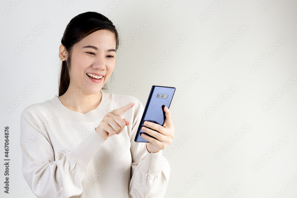 Asian beautiful woman are chatting or reading or shopping online or doing payment on a smart phone with smiling and happiness Asian beautiful woman are chatting or reading or shopping online or doing payment on a smart phone with smiling and happiness