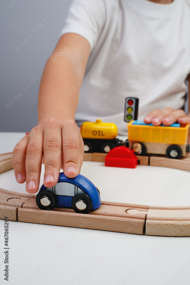 Naklejka premium The boy is playing on the toy wooden road. Top view. Child boy playing in his room with a toy train. Kid's hands close up