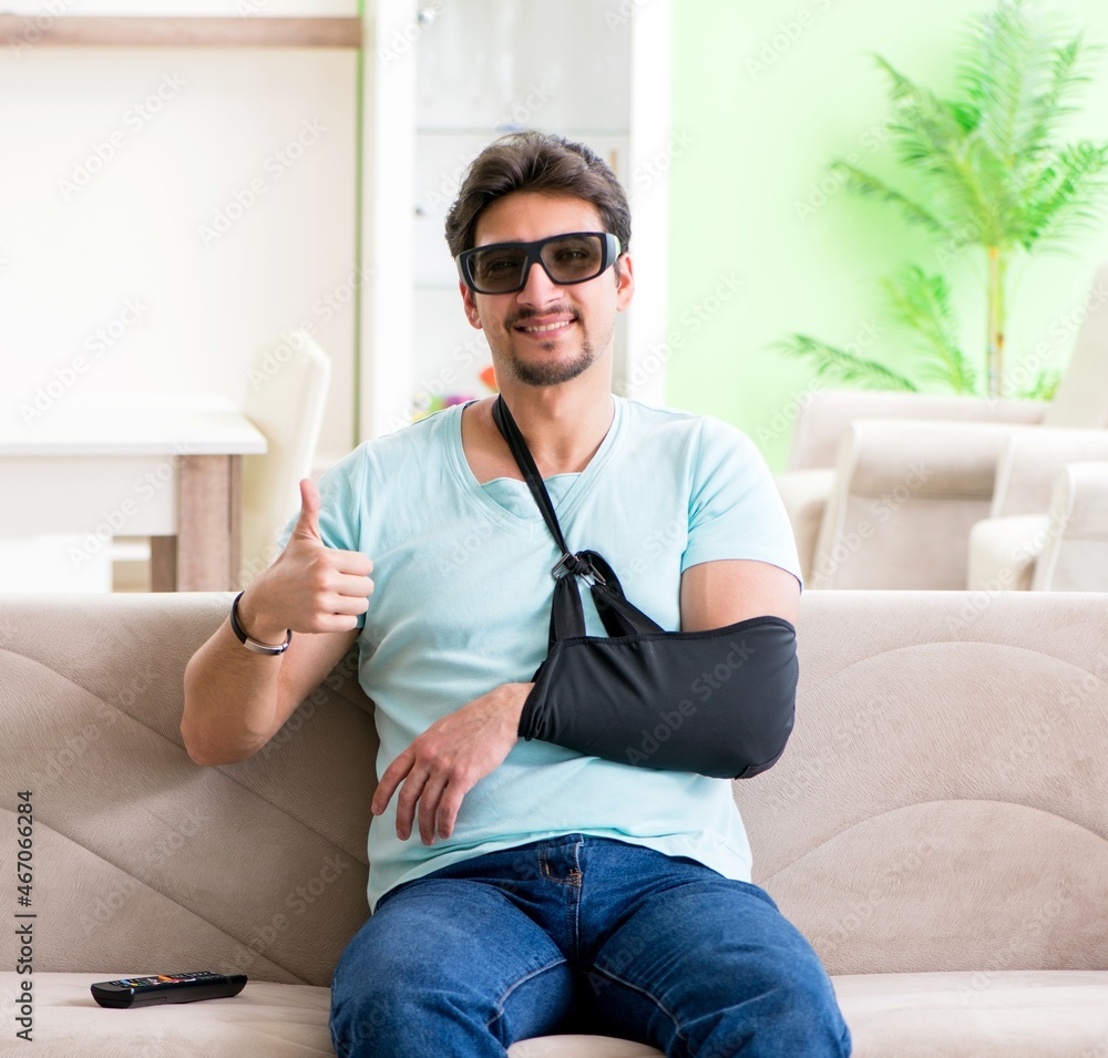 Arm injured man sitting on the sofa watching tv Arm injured man sitting on the sofa watching tv