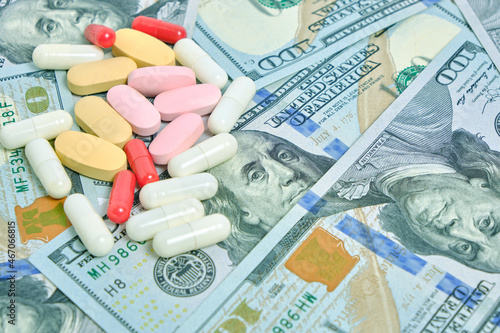 Lot of pills against background hundred dollar bills.Concept of expensive medicine.