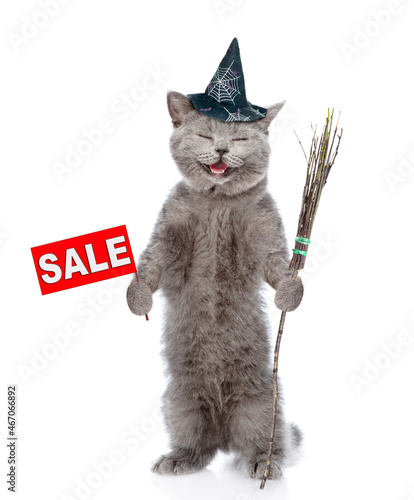 Happy cat wearing hat for halloween holds sales symbol and witches broomstick. isolated on white background