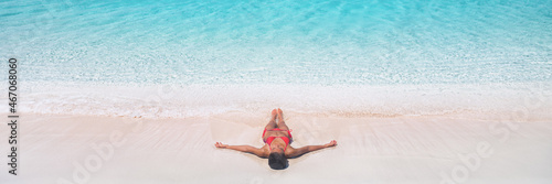 Beach vacation dream Caribbean travel destination bikini woman sunbathing relaxing lying down on pink sand drone view banner landscape of blue waves of water.