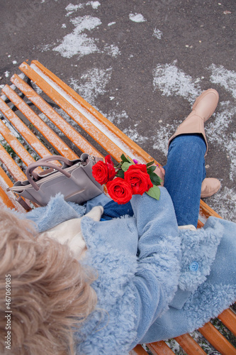 A girl with red roses in her hands in winter on a bench © Альбина Кадочникова