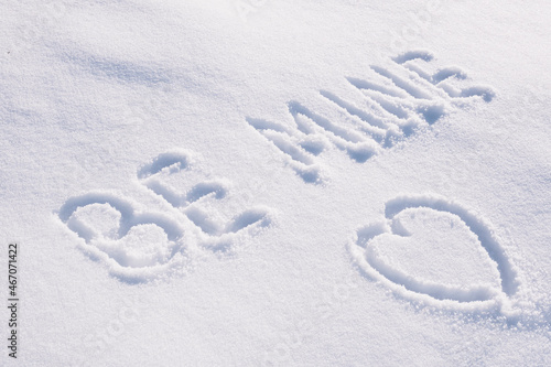 Text Be mine and contour drawing in shape of heart on white snow.