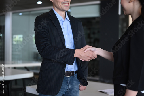 Two smiling business partners shaking hands after negotiations.