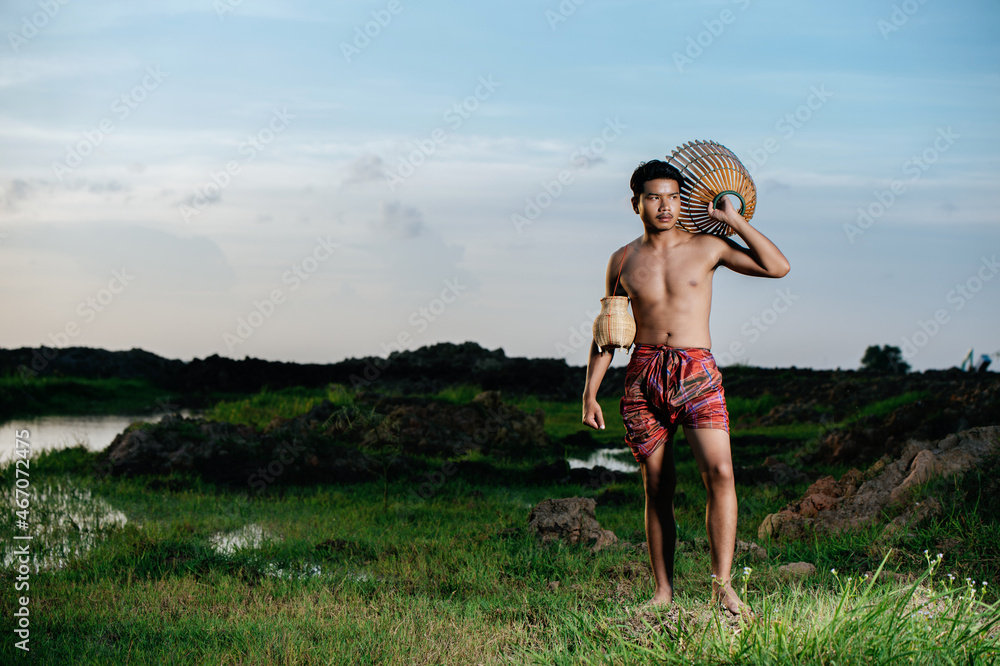Asian young man in loinclothes and bamboo fishing trap
