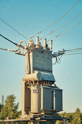 Power transformer with insulators and cables under blue sky