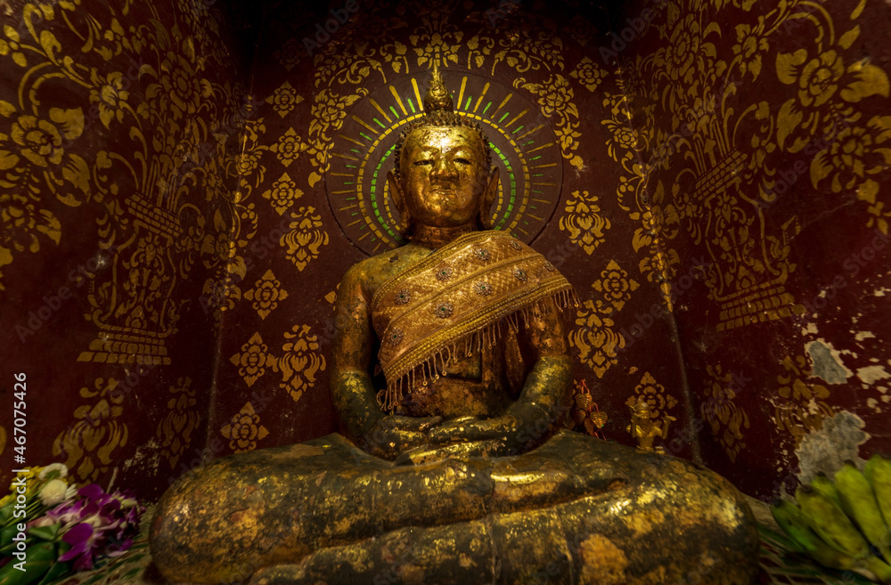 An ancient monumental Buddha statue sitting in meditation posture is covered with gold leaf.