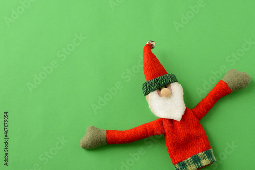 Christmas or New Year background with Santa Claus. Figure of a toy Santa Claus on a green background,  copy space. Christmas decoration handmade/ Christmas time, magic of christmas