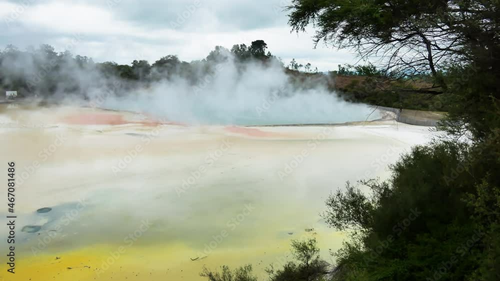 Panning shot of Wai-o-tap Geothermal Wonderland In Rotorua, New Zealand during daytime - Hot springs with rising steam and Colorful surface of different minerals Panning shot of Wai-o-tap Geothermal Wonderland In Rotorua, New Zealand during daytime - Hot springs with rising steam and Colorful surface of different minerals