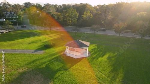 Aerial rotational view of isolated gazebo amidst beautiful lush green garden along busy road. photo