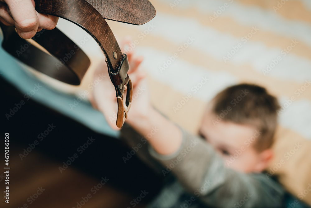 Hand holds leather belt next child is frightened. Family violence concept.Toned.Soft focus.