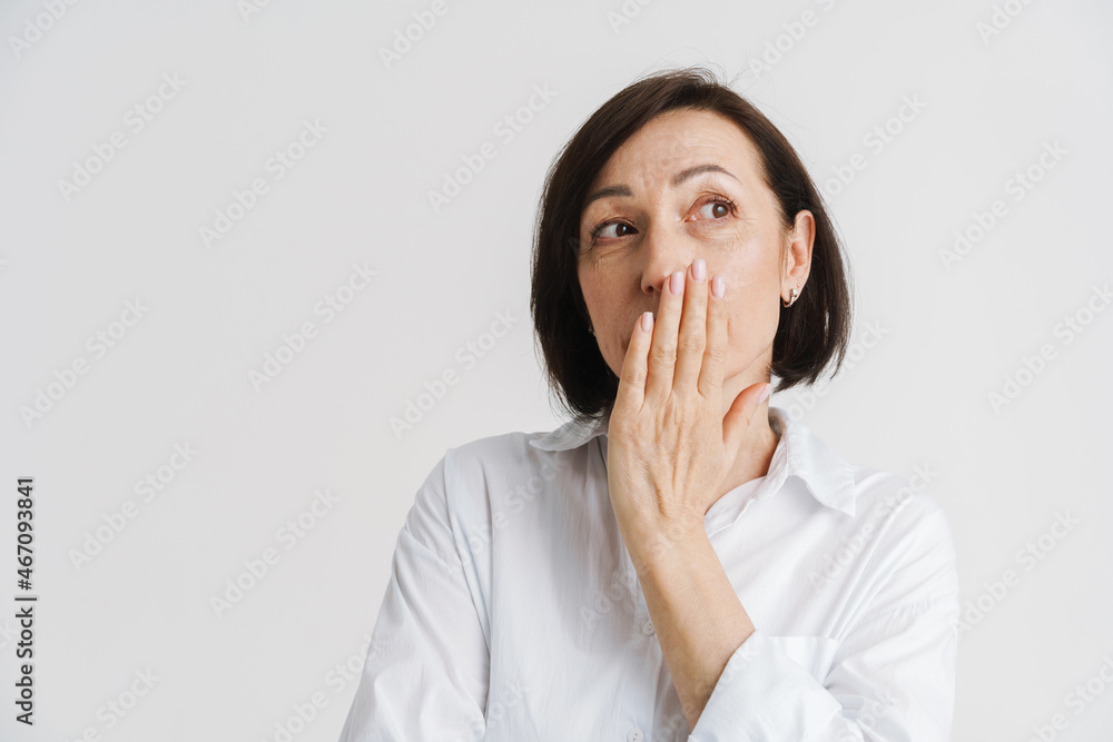 European mature woman looking aside while covering her mouth European mature woman looking aside while covering her mouth