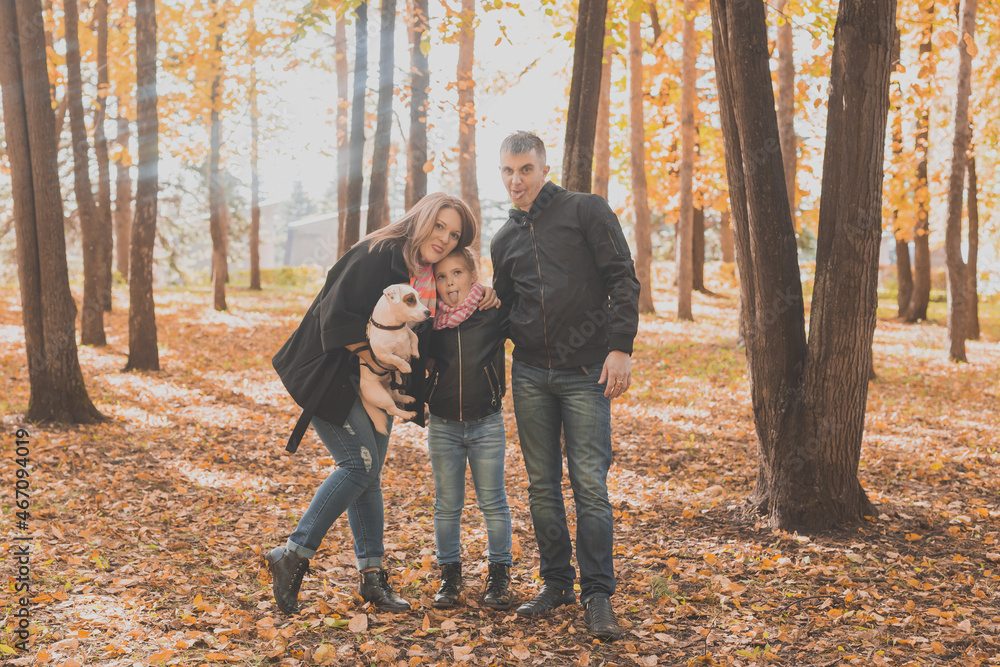 Family spend time in autumn park with a dog. Father, mother and daughter and jack russell terrier dog having fun in fall Family spend time in autumn park with a dog. Father, mother and daughter and jack russell terrier dog having fun in fall