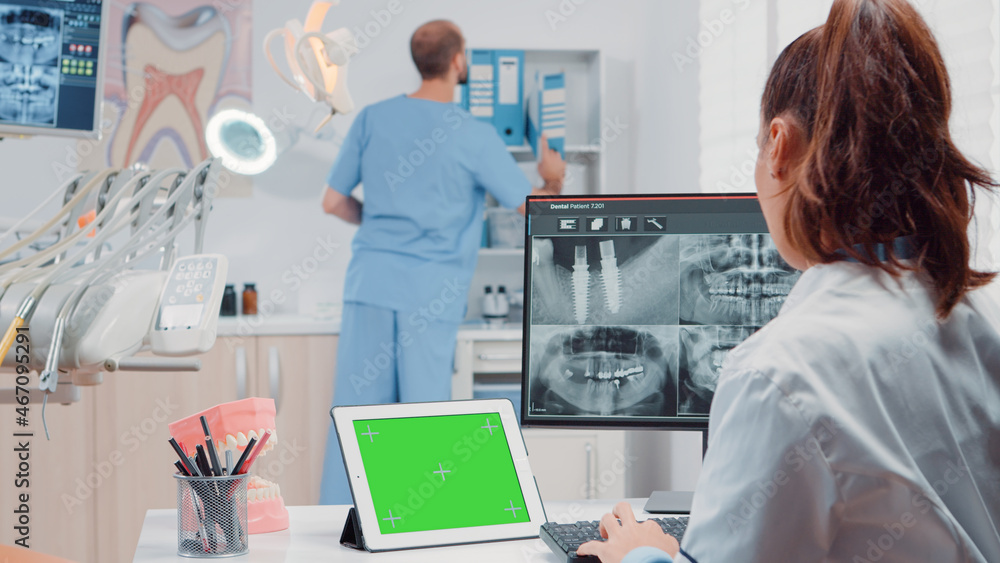 Orthodontist using horizontal green screen on tablet for oral care and dentistry. Woman working as dentist with chroma key and isolated mockup template while looking at teeth scan Orthodontist using horizontal green screen on tablet for oral care and dentistry. Woman working as dentist with chroma key and isolated mockup template while looking at teeth scan