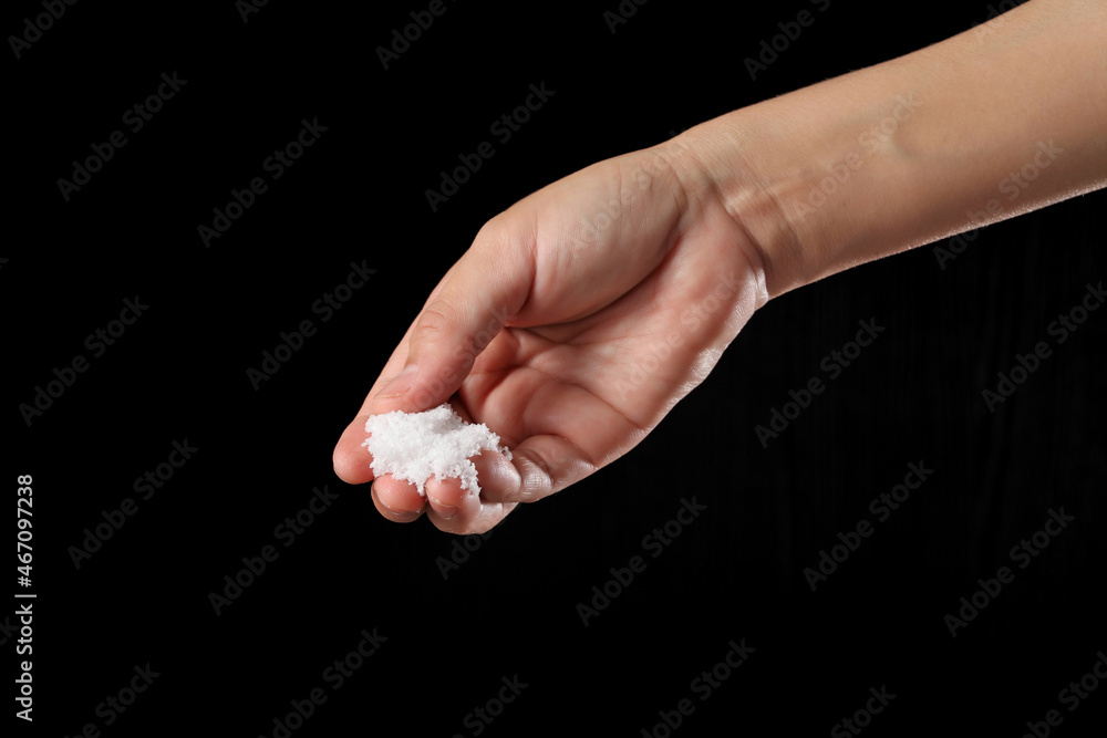 Hand holding sea salt on black background