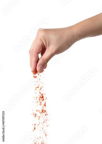 Hand sprinkling cayenne pepper on white background