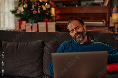 Indisposed man using laptop at home