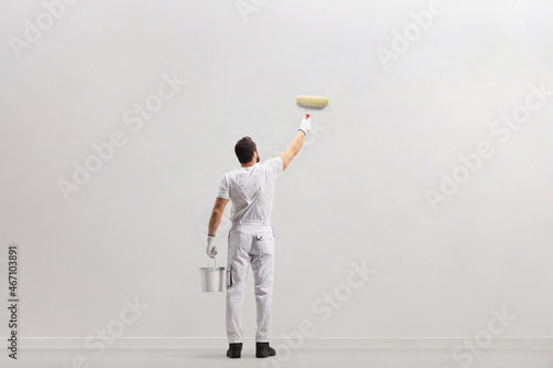 Foto Rear view shot of a painter holding a bucket and painting a wall