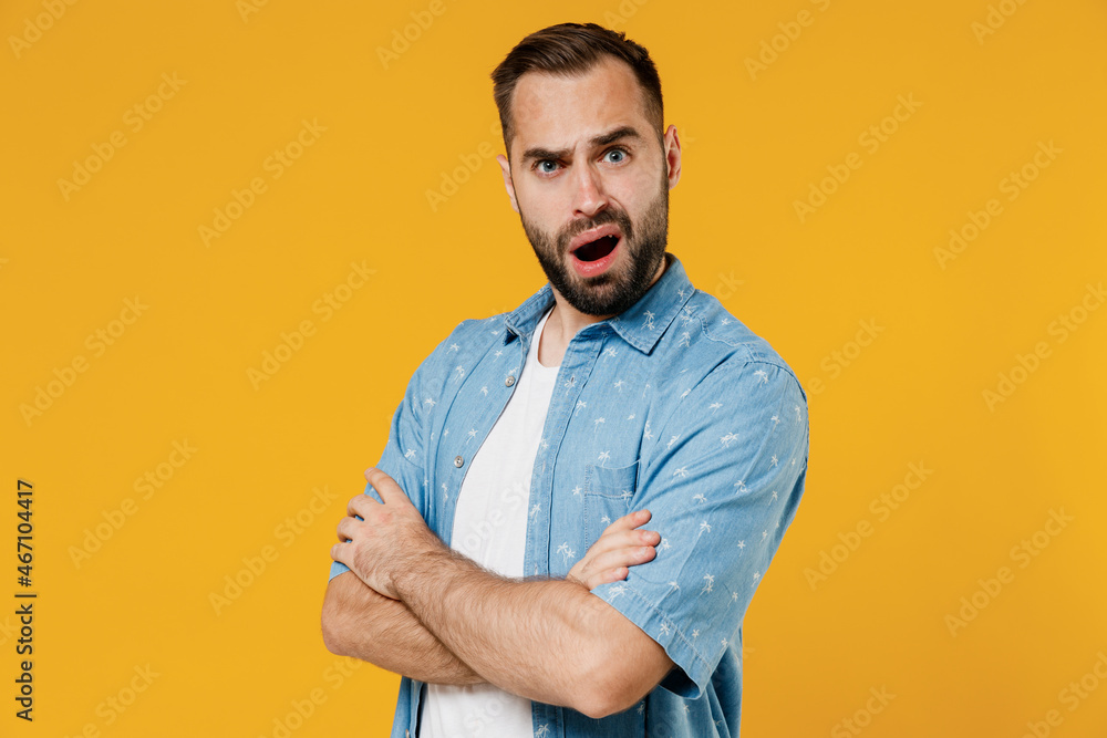Side view young questioned indignant frowning caucasian man 20s wearing blue shirt white t-shirt hold hands crossed folded isolated on plain yellow background studio portrait People lifestyle concept Side view young questioned indignant frowning caucasian man 20s wearing blue shirt white t-shirt hold hands crossed folded isolated on plain yellow background studio portrait People lifestyle concept