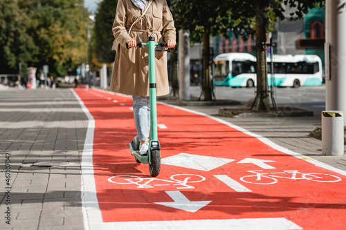 traffic, city transport and people concept - woman riding electric scooter along red bike lane with signs of bicycles and two way arrows on street