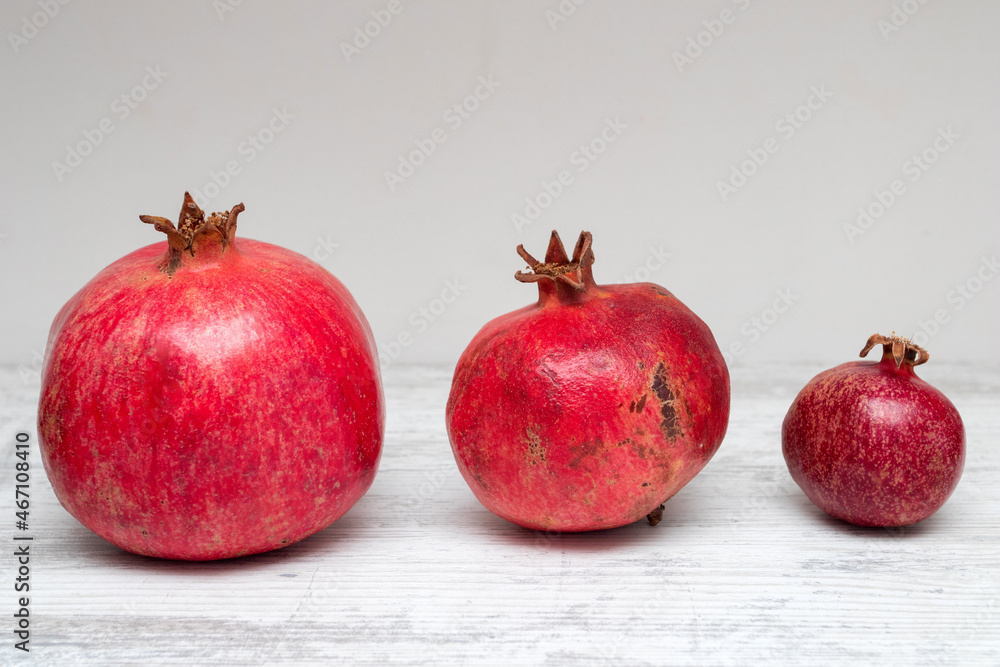 Three pomegranate fruits on a white table Three pomegranate fruits on a white table