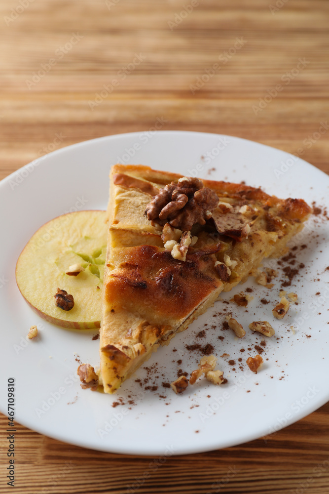 Piece of apple pie on plate on wooden background