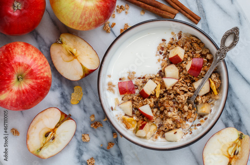 Homemade granola (muesli) with oatmeal, nuts, flaxseed, cornflakes, fresh red apple, cinnamon and yogurt 