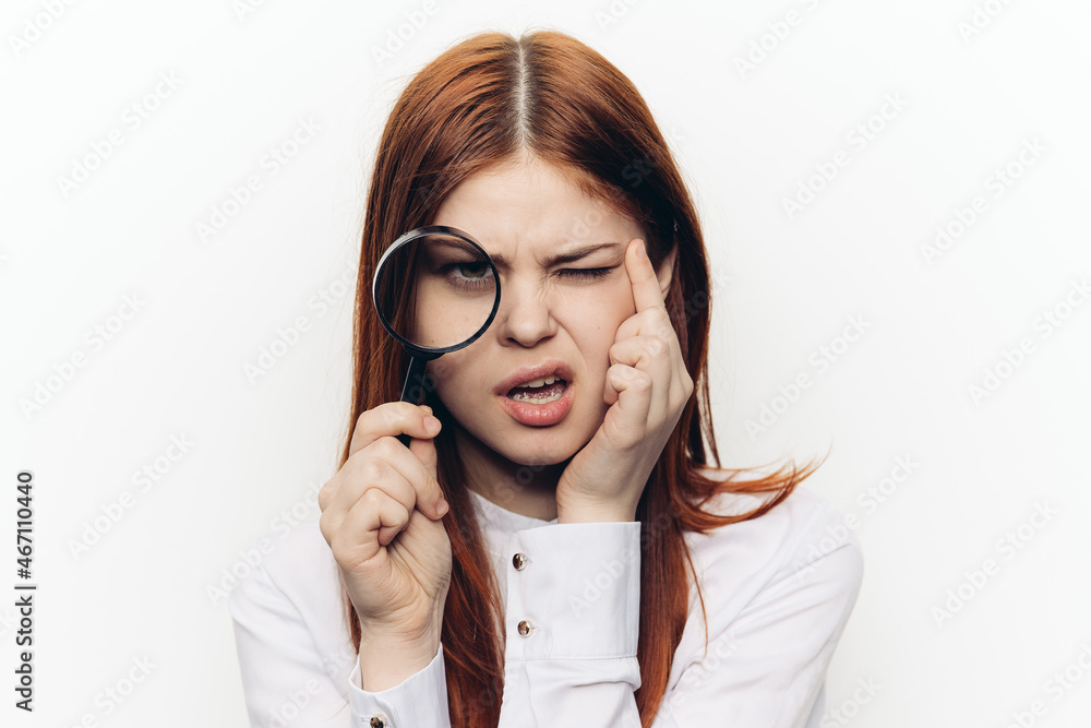 cheerful red-haired woman holding a magnifying glass near her face cheerful red-haired woman holding a magnifying glass near her face