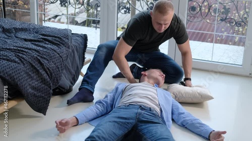 A man provides first aid to a friend with an epileptic seizure photo